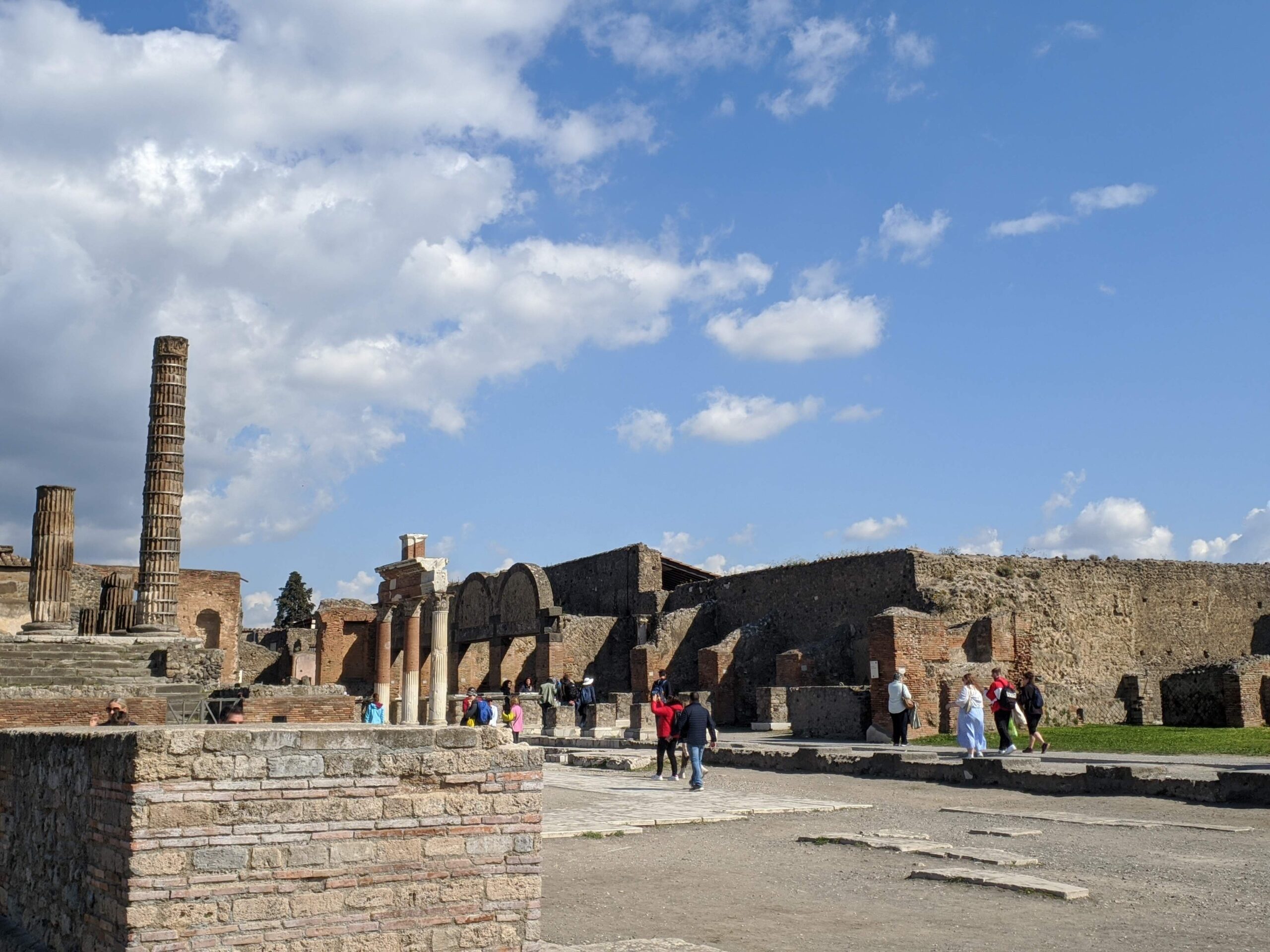 Foto de diversas ruínas de casos e palácios feitas de pedra, é possível ver pessoas andando por entre elas.