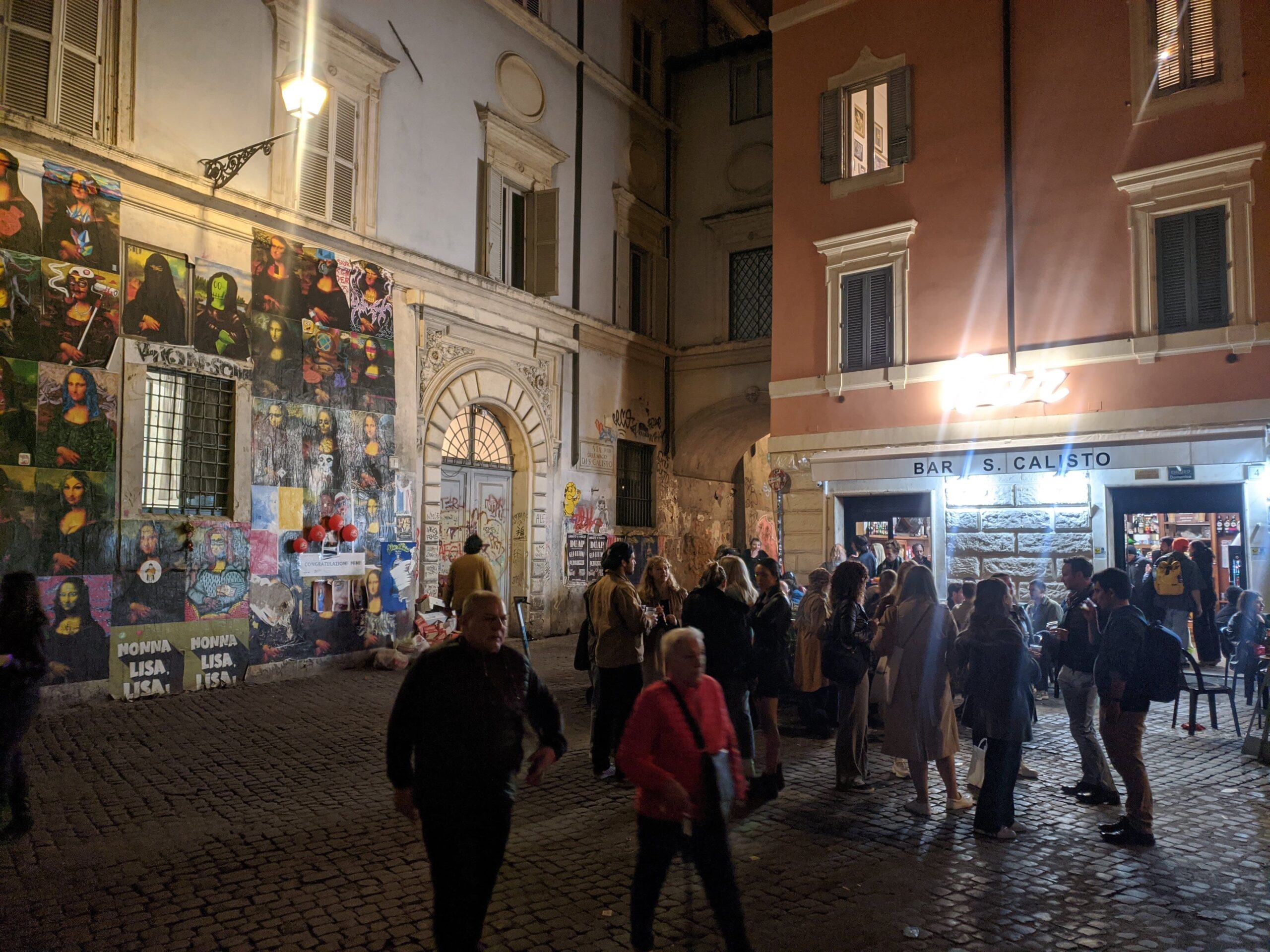 : Fachada colorida e vibrante de um bar, adornada com várias interpretações de arte de rua da Mona Lisa, com pessoas reunidas e conversando na calçada em uma noite animada.