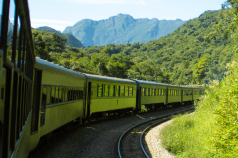 A capa vibrante de um guia turístico com um trem amarelo serpenteando por um vale verdejante, com montanhas majestosas ao fundo sob um céu azul claro