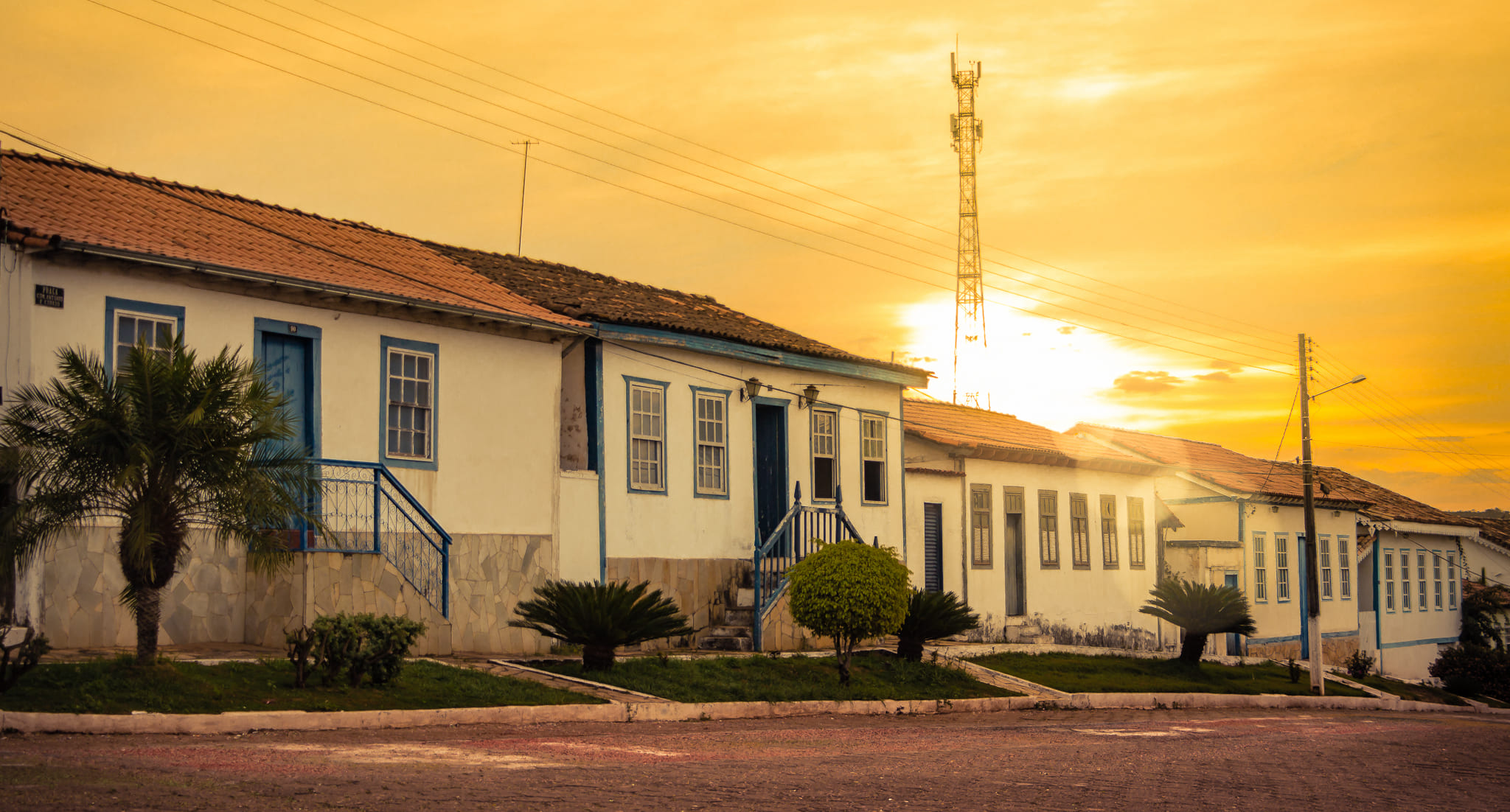 Casas coloniais com fachadas azuis e brancas ao pôr do sol em uma rua tranquila da cidade de Goiás, refletindo o charme histórico e a herança cultural como Patrimônio Mundial da UNESCO.