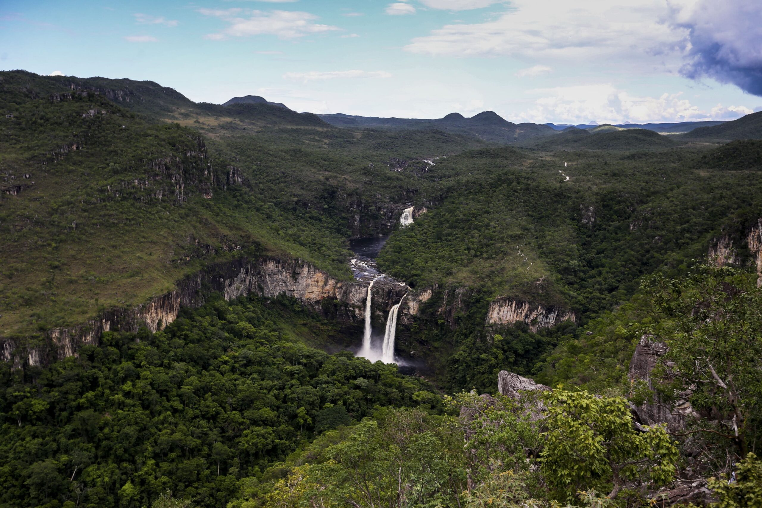 Cachoeira de 120 metros caindo de um penhasco no Parque Nacional da Chapada dos Veadeiros, cercada por uma vasta vegetação típica do Cerrado, um espetáculo natural reconhecido pela UNESCO.