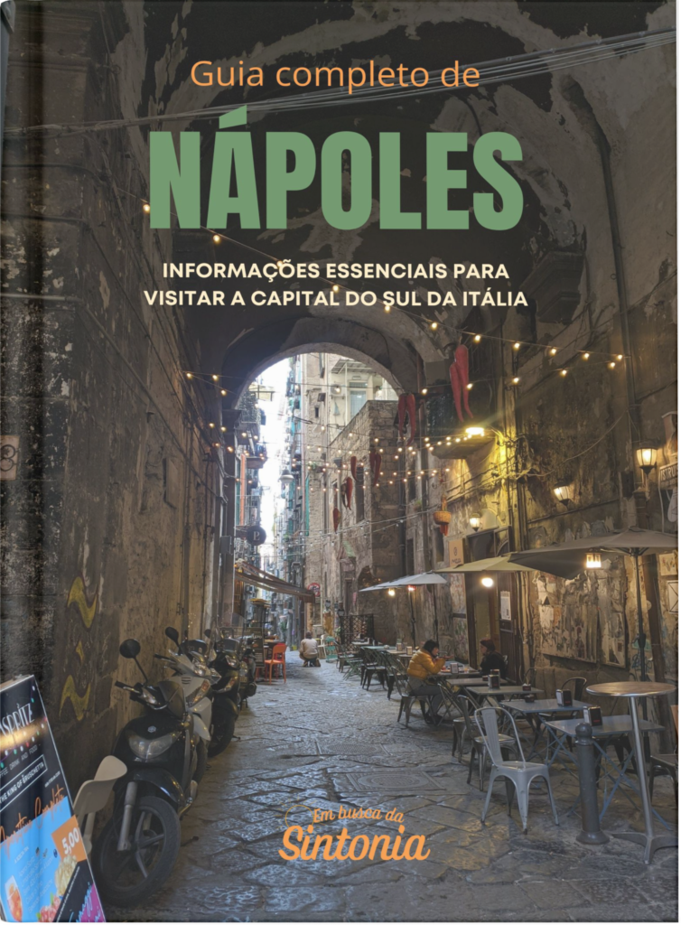 Foto de uma viela iluminada em Nápoles representada como se fosse a capa de um livro, como o escrito "Guia completo de Nápoles" e o logo do Em Busca da Sintonia em baixo.