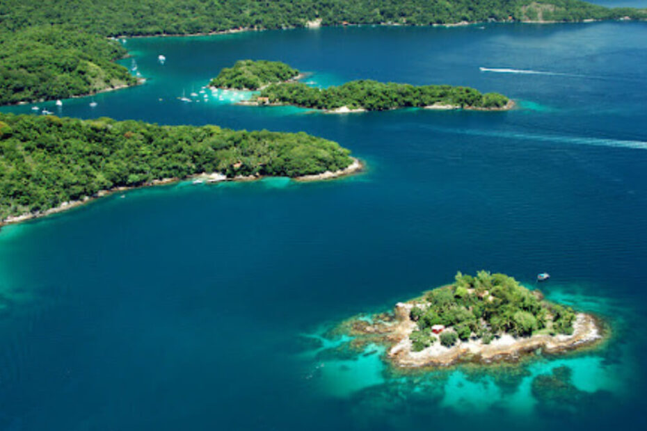 Vista aérea de um conjunto de ilhas tropicais com águas azul-turquesa e vegetação densa, ilustrando um destino turístico possivelmente popular para atividades aquáticas e relaxamento.